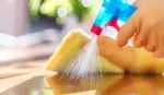 Close up of a cleaning product being sprayed and wiped down on a kitchen surface