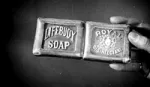 A black and white image of a hand holding an original Lifebuoy bar of soap